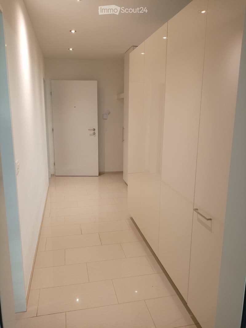 Empty hallway with white tiles, white walls, white doors, and white cabinets