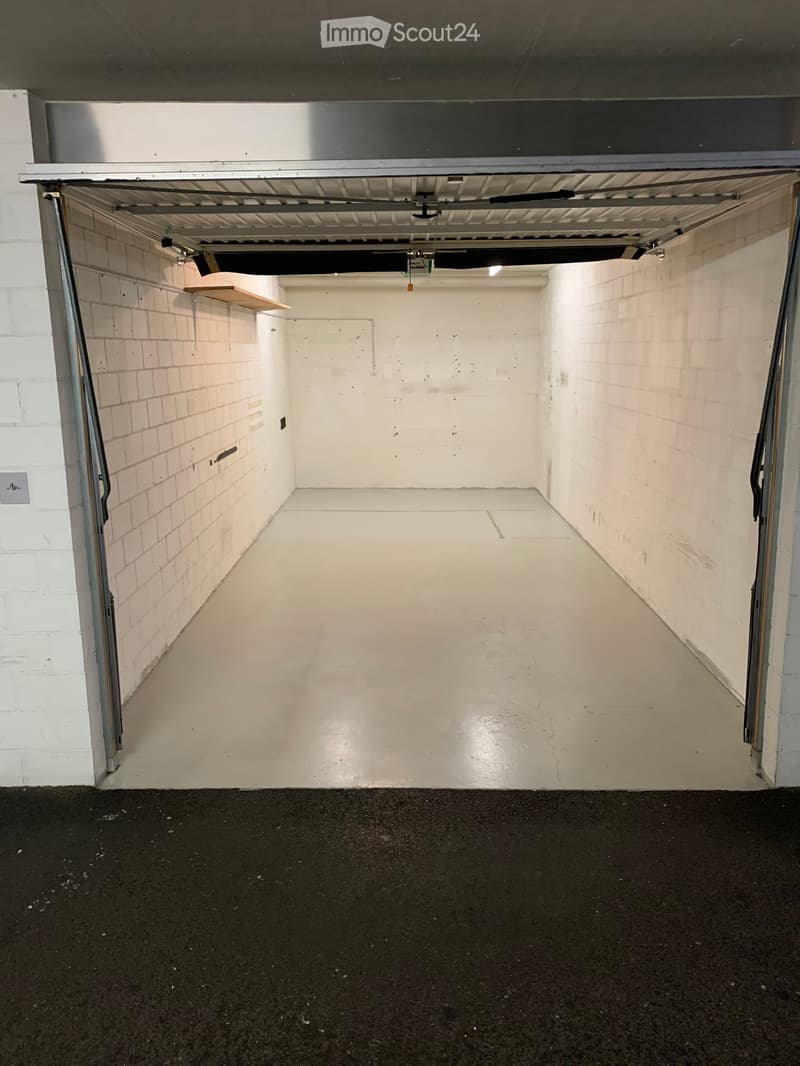 Empty garage with white walls and floor, metal ceiling, and an open door