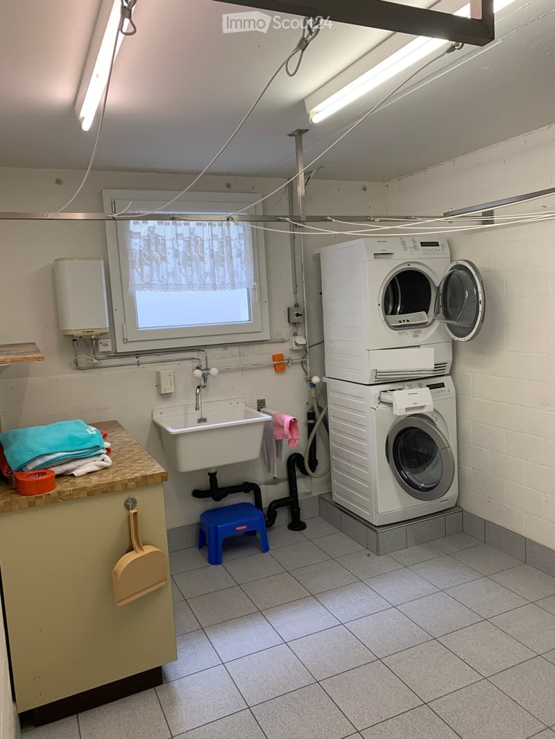 A small laundry room with a washing machine, a dryer, a sink, and a window.