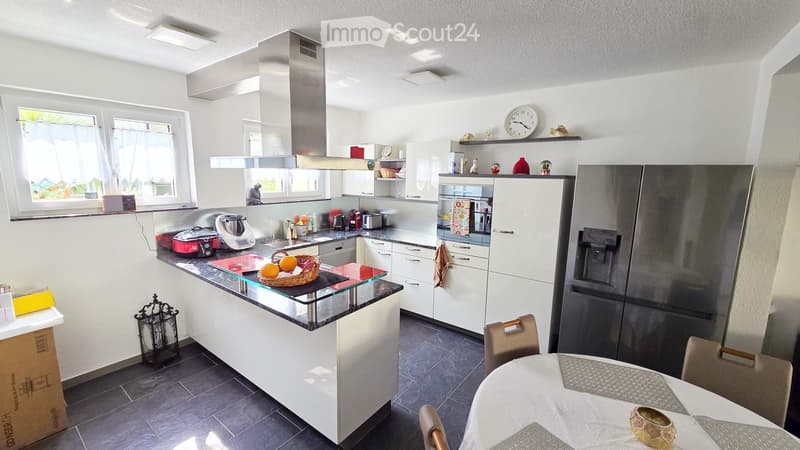 island counter, modern appliances, white cabinets, black tiled floor, stainless steel fridge