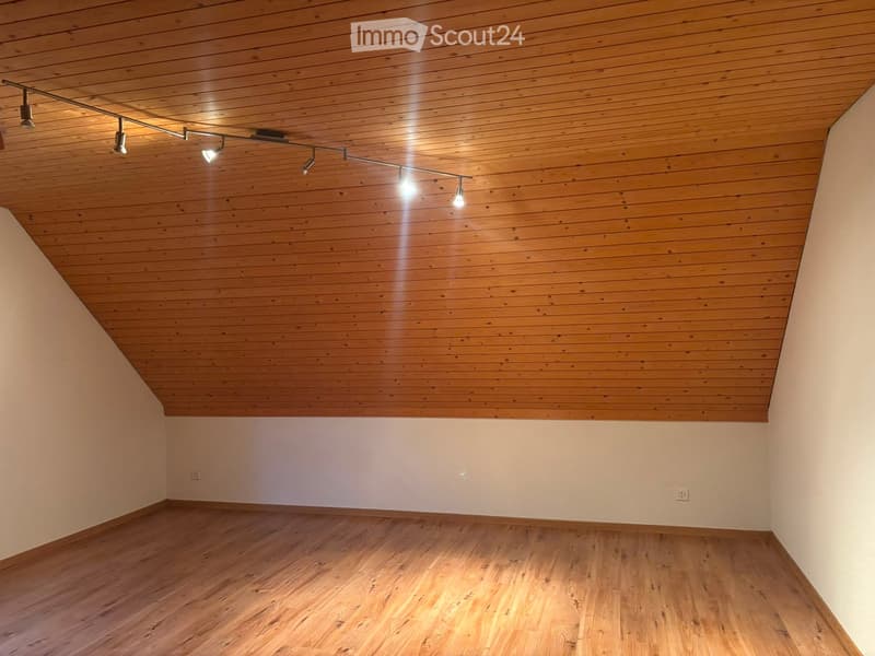 Empty room with wooden floor and paneled wooden ceiling, track lighting fixture, white walls, and electrical outlets.