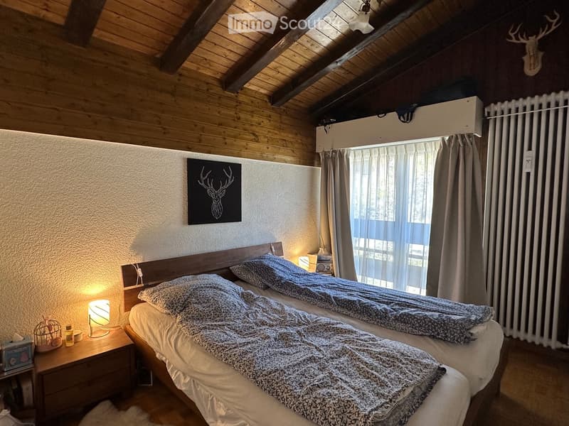 Cozy bedroom with two single beds, wooden nightstand, lamp, radiator, and decorative items.