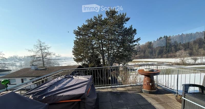 Balcony with a fountain, covered hot tub, and a view of a snowy landscape and trees.