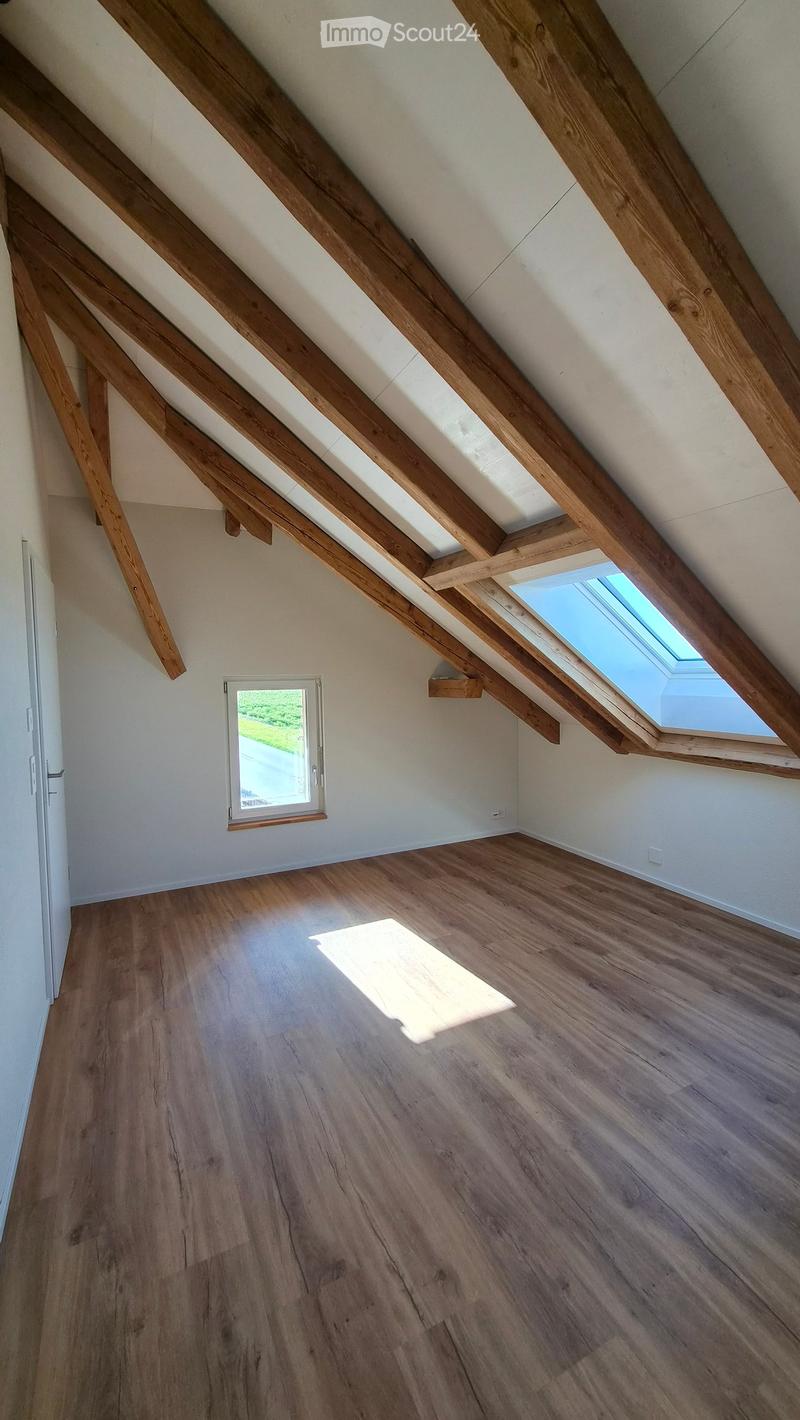 Empty attic space with wooden beams, wooden flooring, and skylight windows allowing natural light.