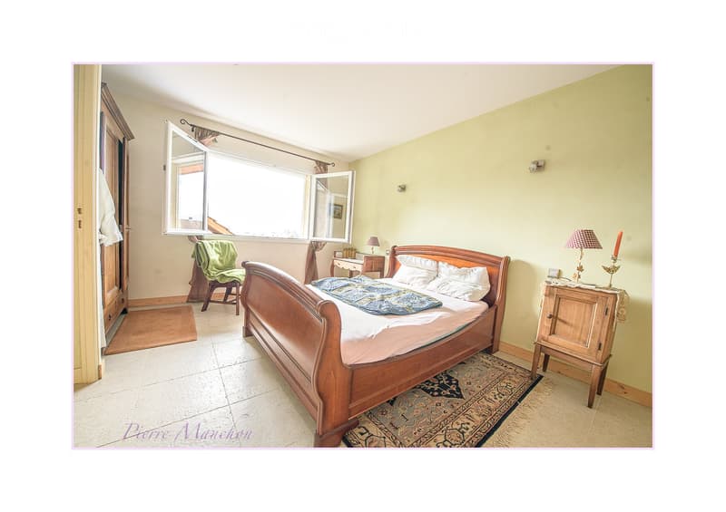 Cozy bedroom with a wooden bed, nightstands, lamps, a chair, and a large window with open shutters.