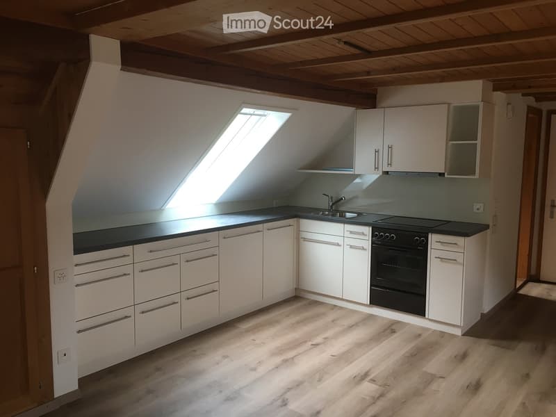 Kitchen, white cabinets, black countertop, wooden floor, ceiling fan, sink, stove, oven, skylight window