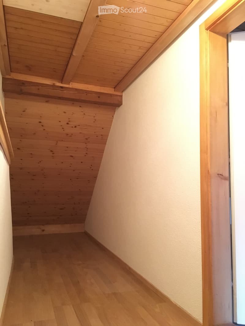 Small room with wooden ceiling and flooring, white walls