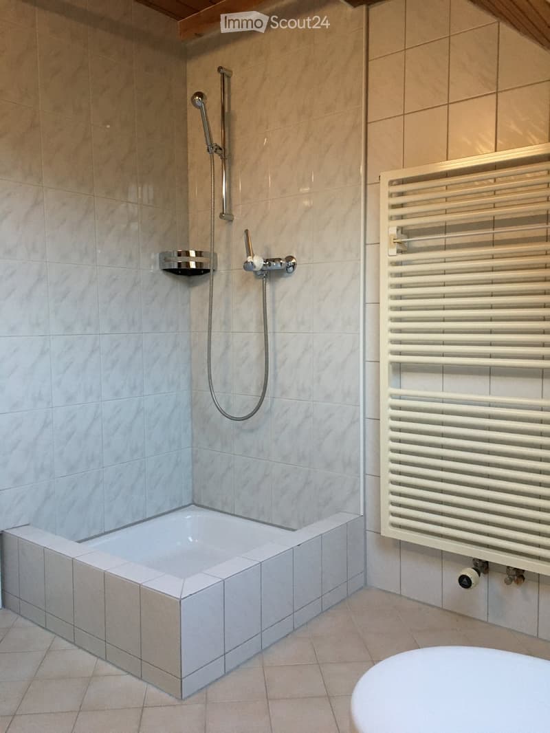Bathroom with walk-in shower, bathtub, towel rack, and tiled flooring.