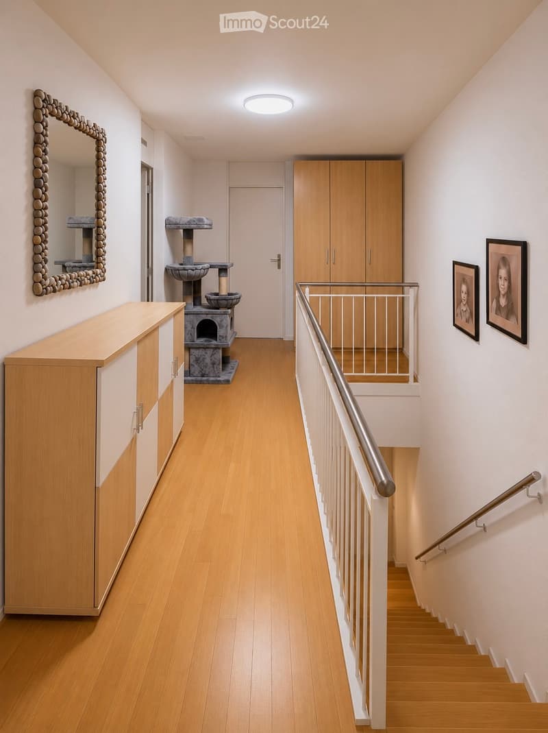 Modern hallway with wooden flooring, white walls, built-in wooden cabinetry, staircase with metal railing, and cat furniture including a scratching post and water fountain.