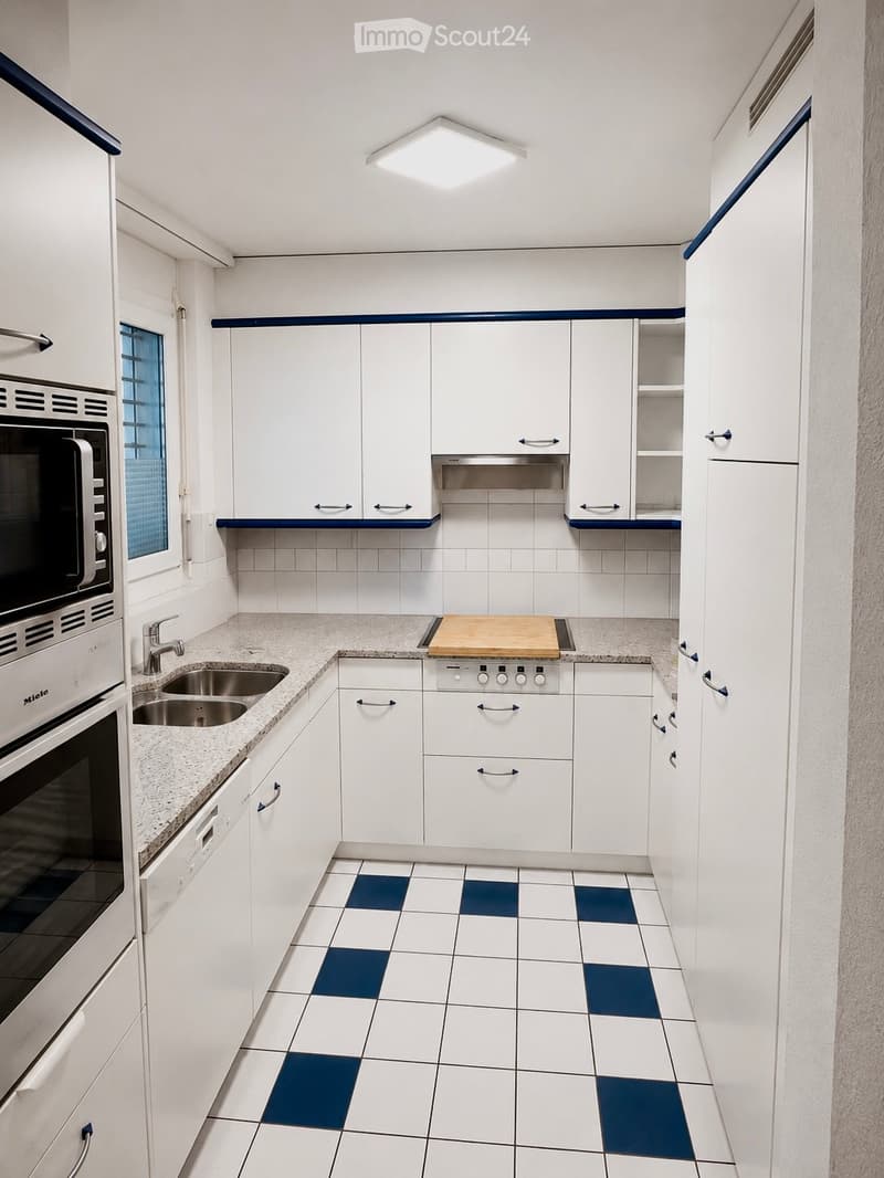 Modern kitchen with white cabinets, granite countertops, stainless steel appliances, and a double sink.