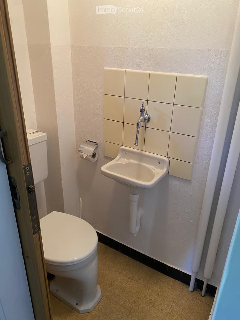 Compact bathroom with a toilet, sink, and faucet, featuring tiled walls and a small window.