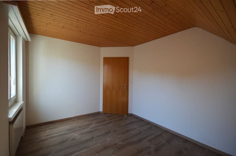 Empty room with wooden floor, white walls, wooden door, and wooden ceiling. No furniture or equipment present.