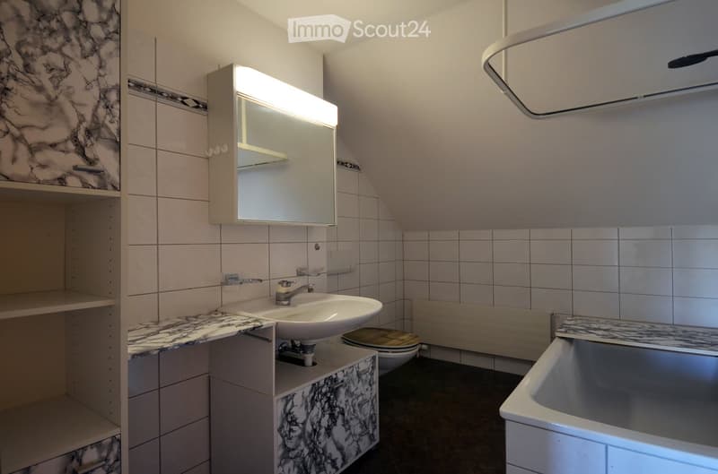 Modern bathroom with a white sink, marble-patterned tiles, a built-in mirror cabinet, and a bathtub.