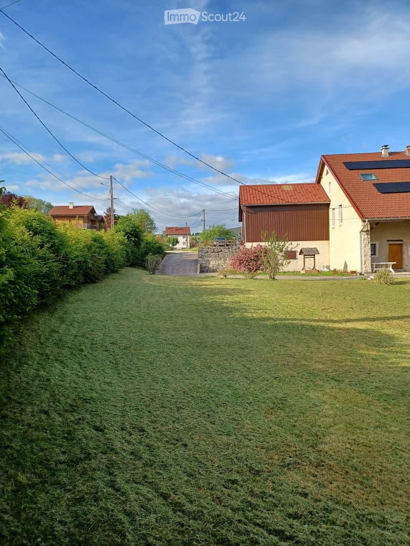 Two-story house with red-tiled roof, solar panels, and a well-maintained lawn in front.