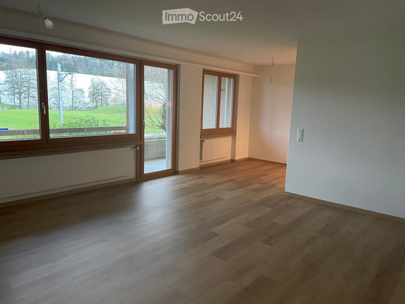 Empty room with wooden flooring, large windows, and radiators. No furniture or equipment present.