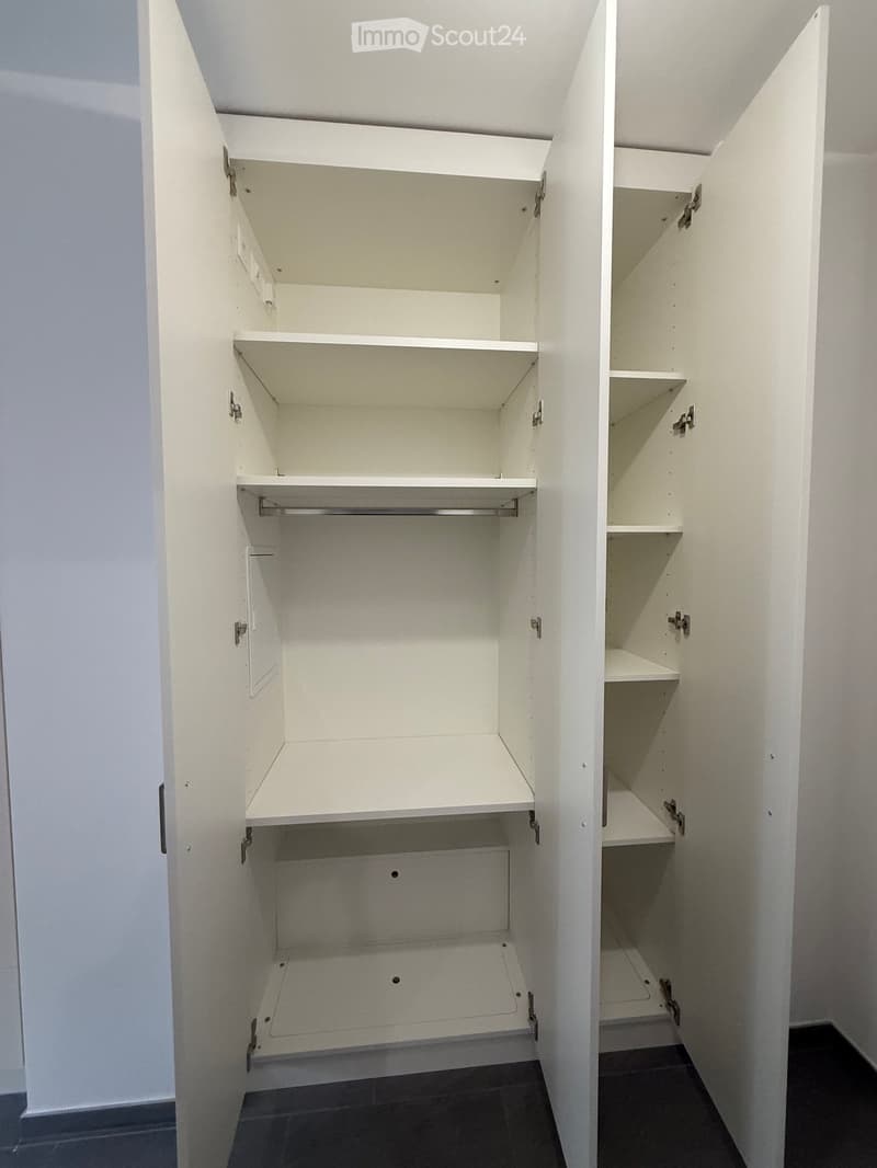 Empty built-in closet with white shelves and drawers, no items inside.