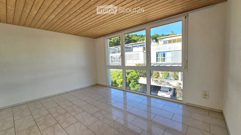 Empty room with tiled floor, large windows, and wooden ceiling. No furniture or equipment visible.
