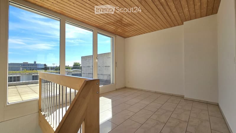 Empty room with wooden ceiling, tiled floor, large windows, and a wooden railing leading to a balcony.
