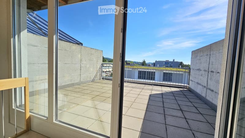 Balcony with tiled floor, metal railing, and open views of the surrounding area under a clear blue sky.