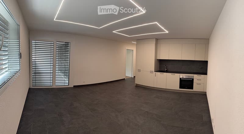 Modern kitchen with white cabinets, dark countertops, and built-in appliances. Features large windows with blinds and recessed LED lighting.