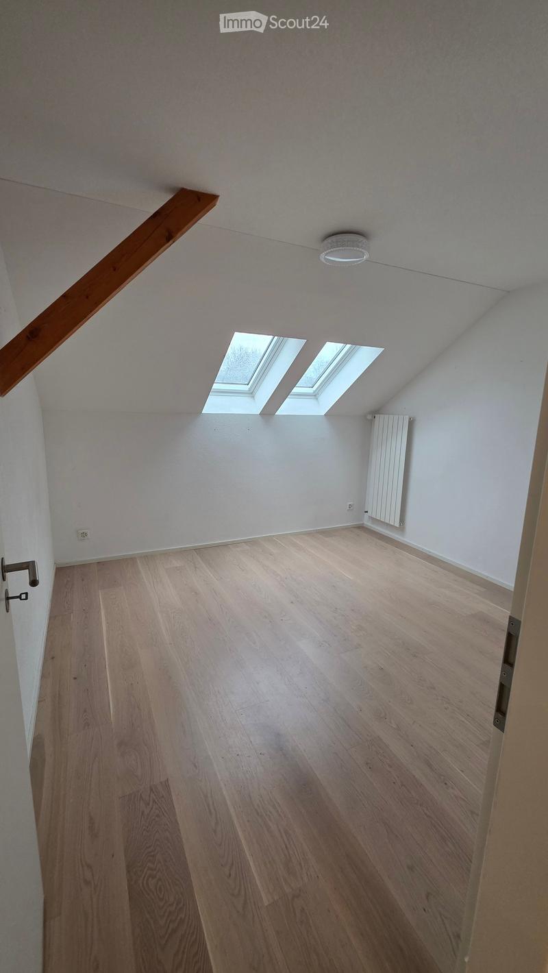 empty room, wooden floor, white walls, two skylights, wooden beam, radiator