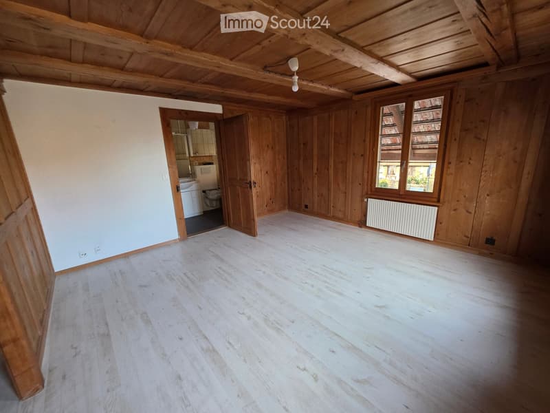 Empty room with wooden floors, white walls, wooden ceiling, window with white frame