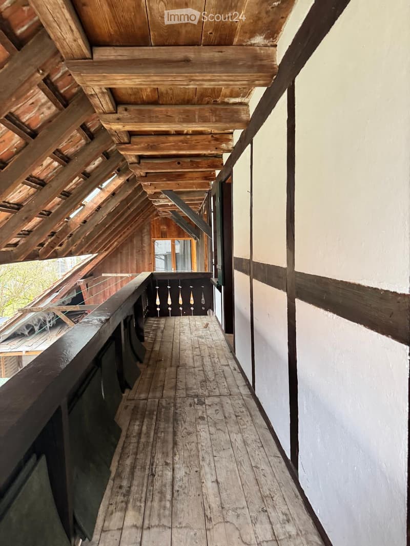 Balcony of the room with wooden floor, wooden ceiling, railing, wooden beams