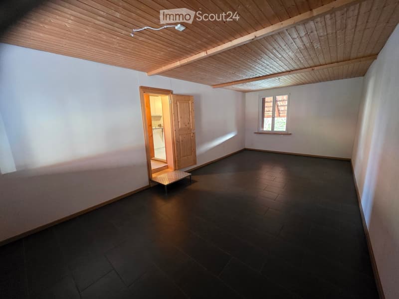 Empty room with wooden ceiling, tile flooring, white walls, wooden floor, large window