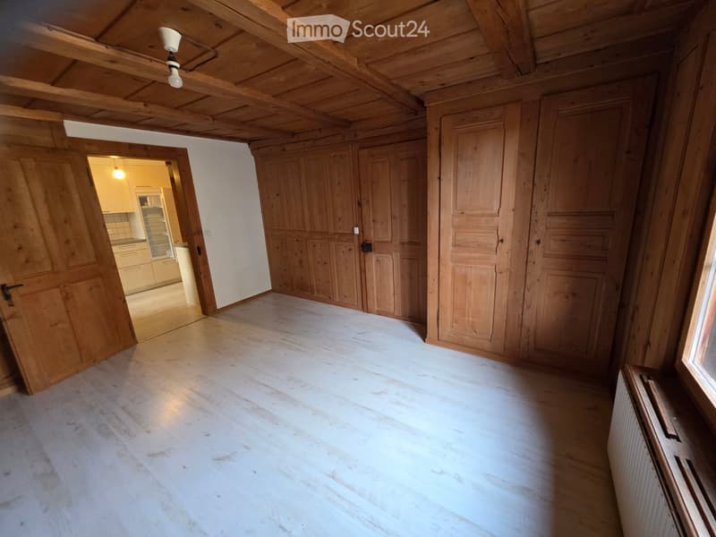 wooden floor, wooden wall panels, white painted wall, central lamp, open door, radiator, view of a hallway