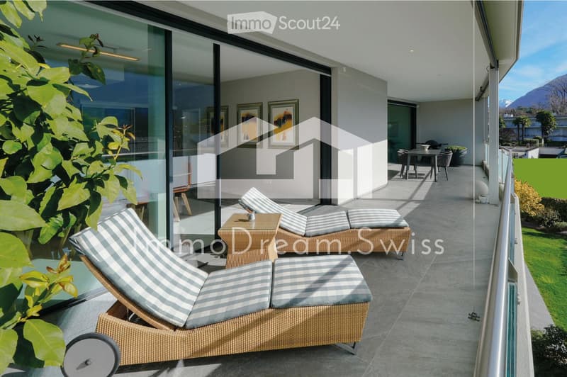 Balcony with sun loungers, a small table, and chairs, overlooking a scenic mountain view.