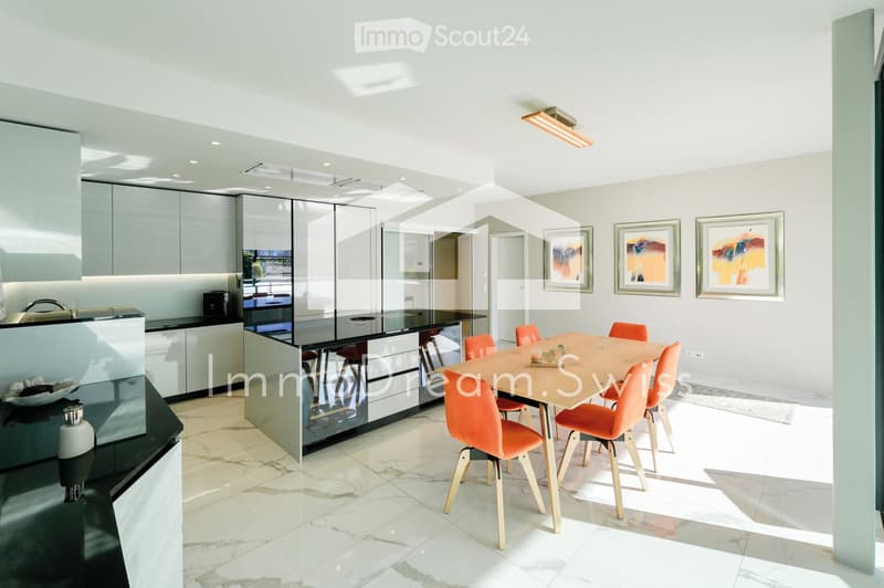 Modern kitchen and dining area with sleek white cabinets, a black countertop, a central island, and a dining table with orange chairs.