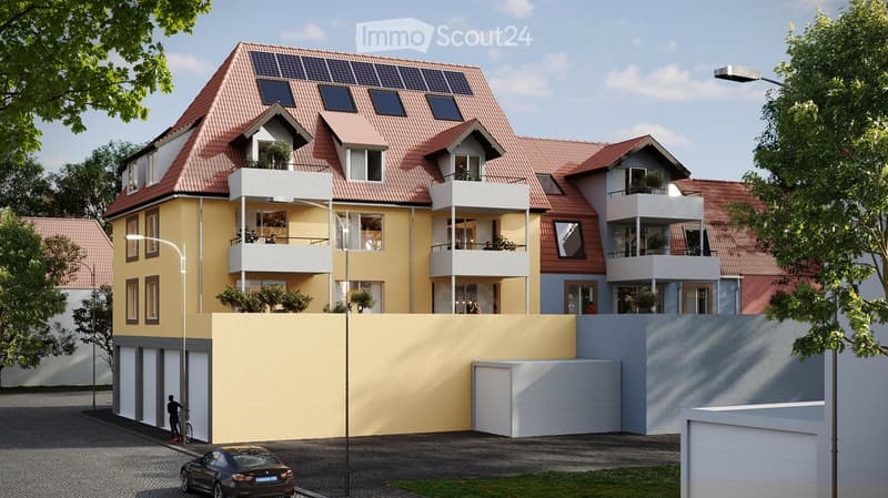 Modern multi-story residential building with balconies, solar panels on the roof, and a garage. The building features a mix of yellow and gray facades with large windows and a contemporary design.