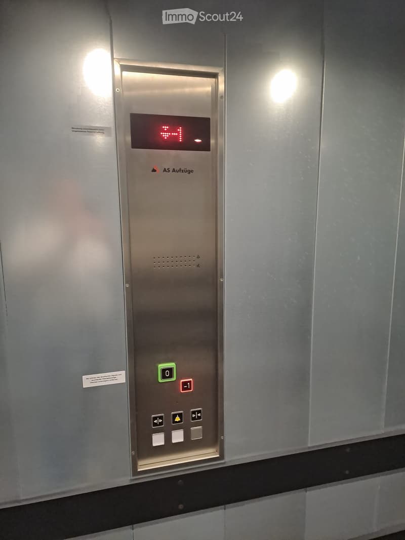 Elevator control panel with digital display showing floor number, buttons for floor selection, and directional arrows.