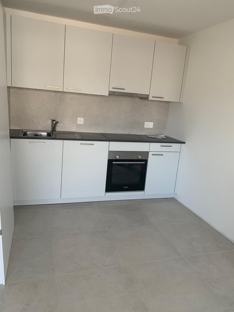Modern kitchen with white cabinets, a sink, a faucet, and an oven. The floor is tiled, and the walls are painted in neutral tones.