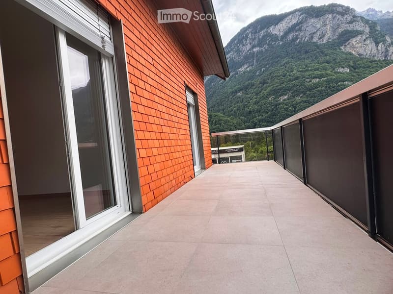 Balcony with tiled floor, glass sliding door, and a scenic mountain view in the background.