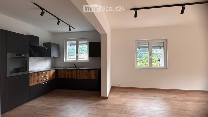 Empty room with wooden flooring, white walls, and large windows. No furniture or equipment present.