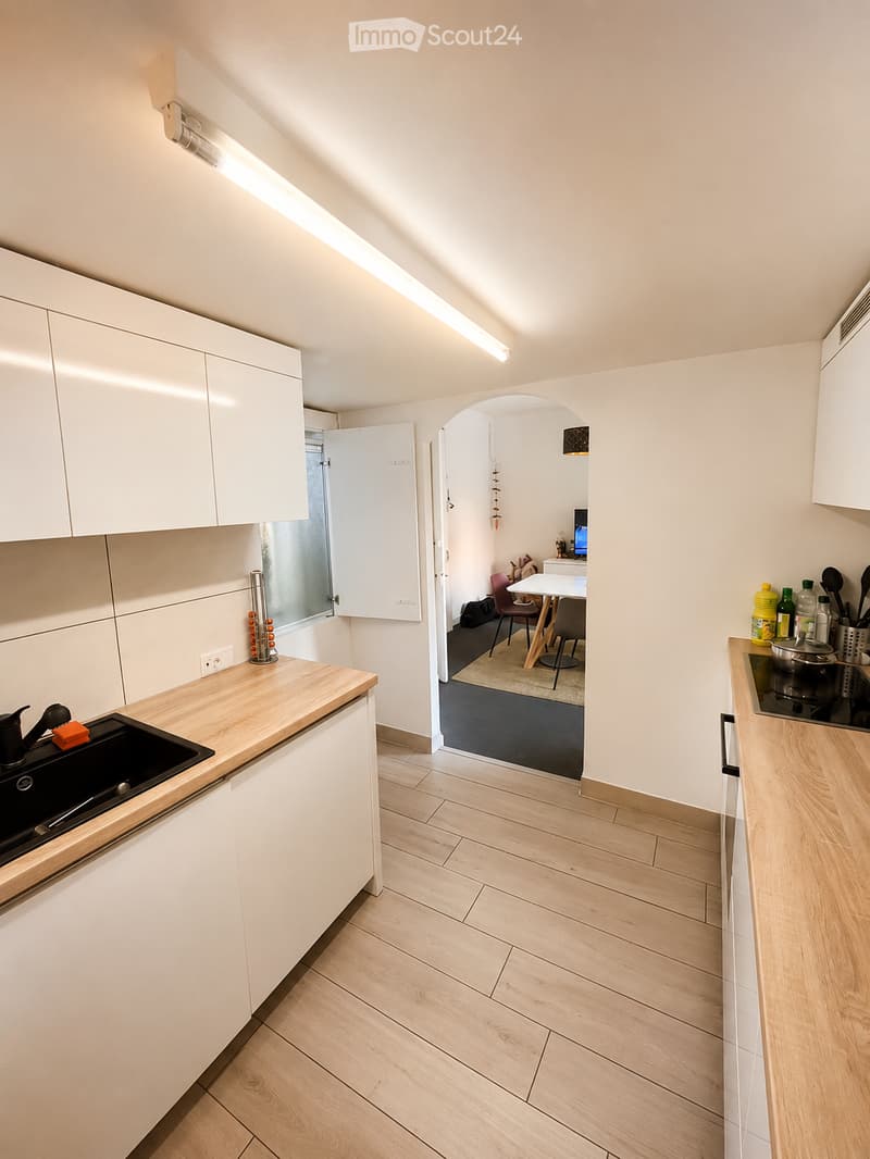 Modern kitchen with white cabinets, wooden countertops, and a sink. Adjacent dining area with a table and chairs.
