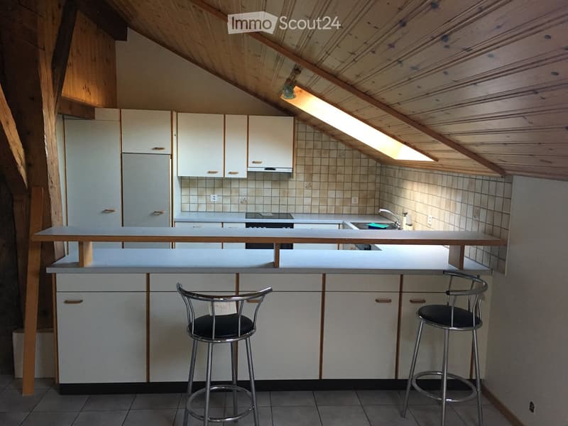 Modern kitchen with white cabinets, a central island, and two bar stools. Features include a refrigerator, oven, and sink.