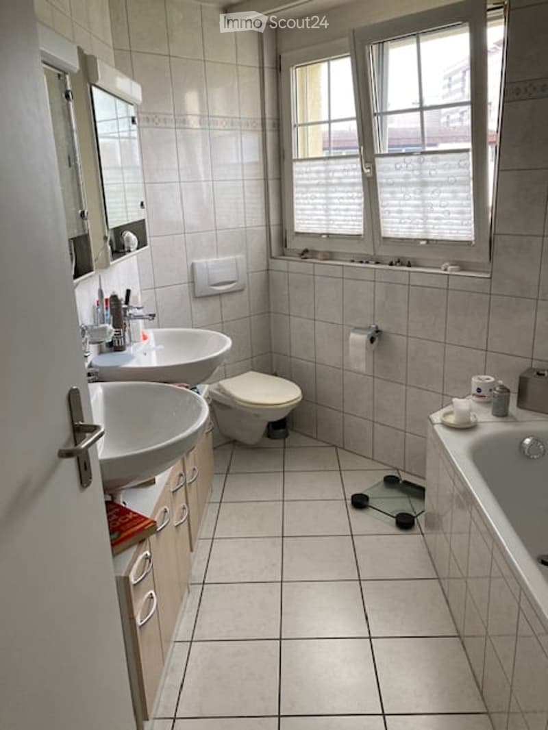 Bathroom with two sinks, a toilet, a bathtub, a mirror, and a scale on the floor.