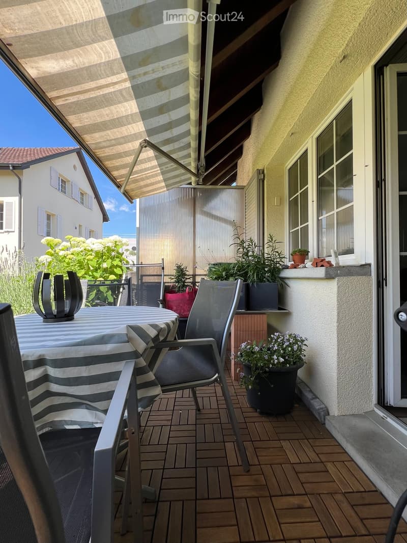 Balcony with tiled floor, table, chairs, candle holder, and potted plants.