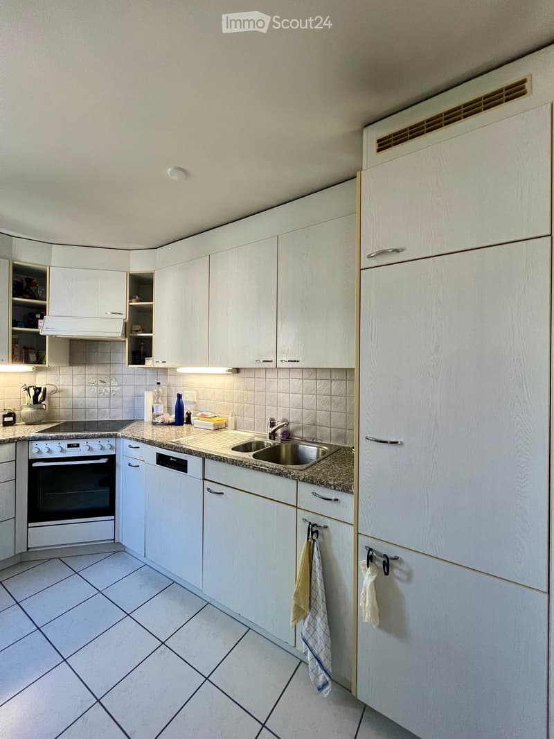Modern kitchen with white cabinets, granite countertop, stainless steel sink, and built-in oven and dishwasher.