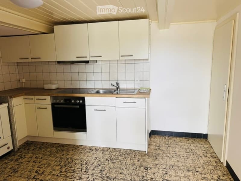 Modern kitchen with white cabinets, granite countertop, stainless steel sink, and built-in oven.