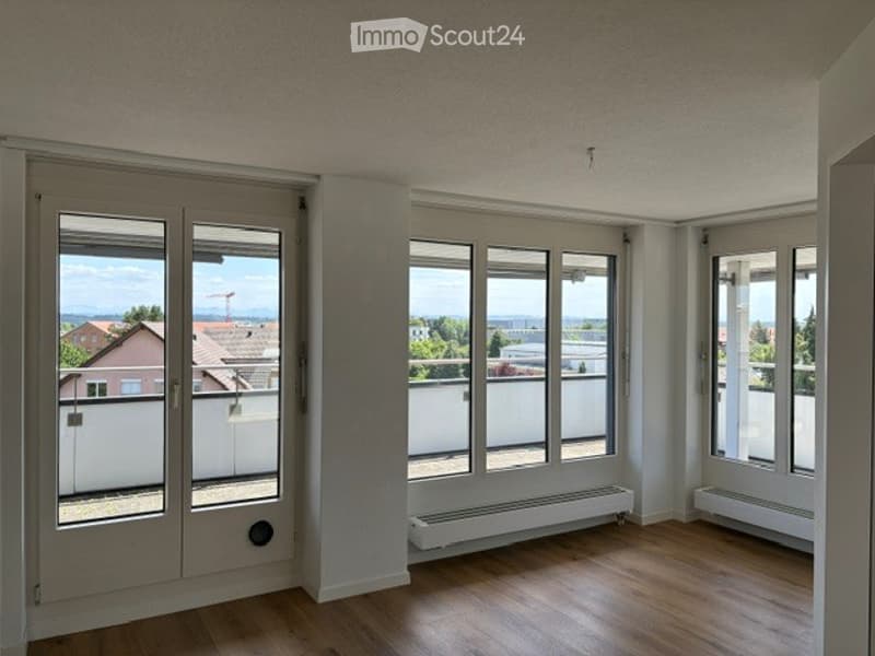 Empty room with wooden flooring, large windows, and white walls. No furniture or equipment present.