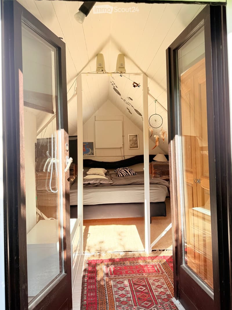 Cozy attic bedroom with slanted ceilings, a lofted twin-sized bed, nightstand, dreamcatcher, and decorative rug.