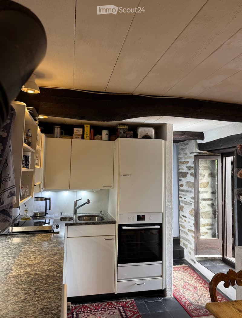Modern kitchen with white cabinets, granite countertops, stainless steel sink and faucet, built-in oven, coffee maker, and various kitchen items on the counter.