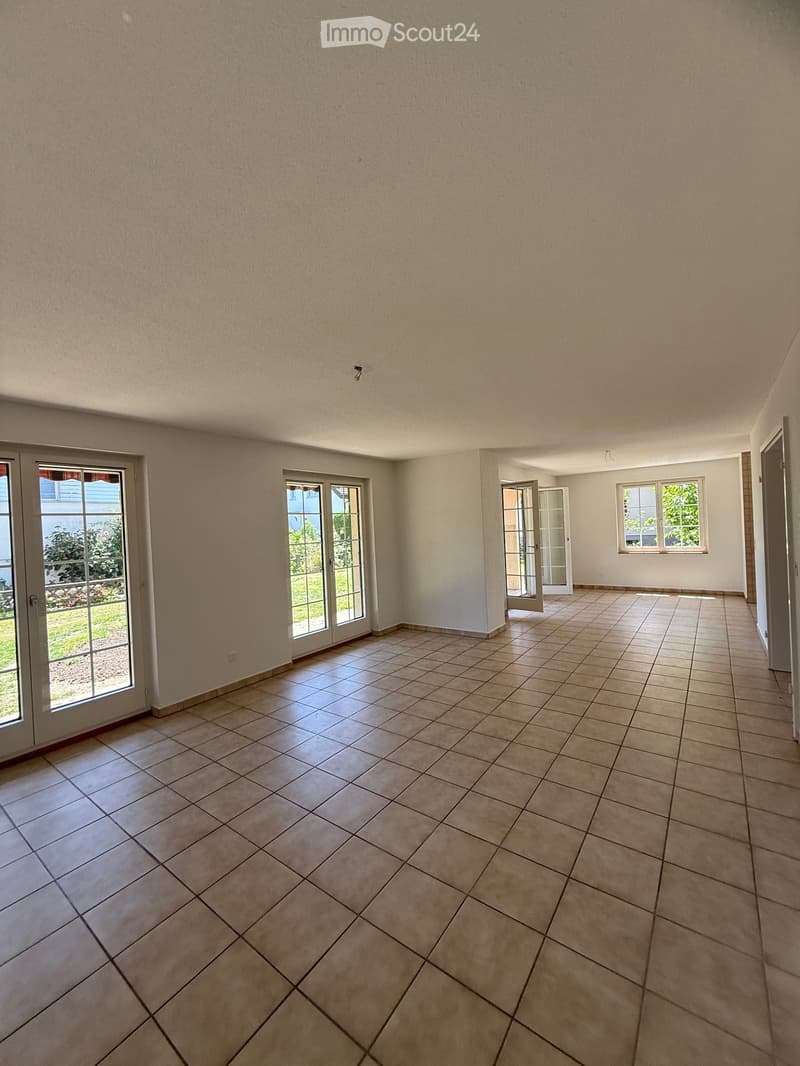 Empty room with tiled floor, large windows, and sliding glass doors leading to an outdoor area.