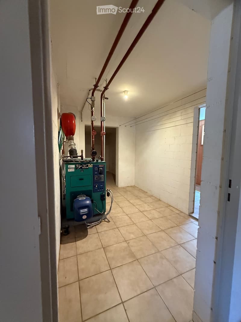 Empty hallway with tiled floor, white walls, and a green utility box with pipes and gauges on the left side.