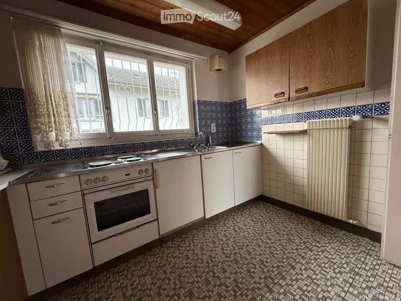 kitchen with blue and white tiles, stainless steel appliances, wooden cabinets, white countertop