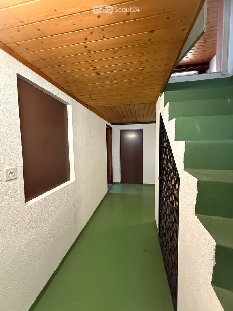 Raised ground floor, wooden ceiling, white walls, green floor, two doors