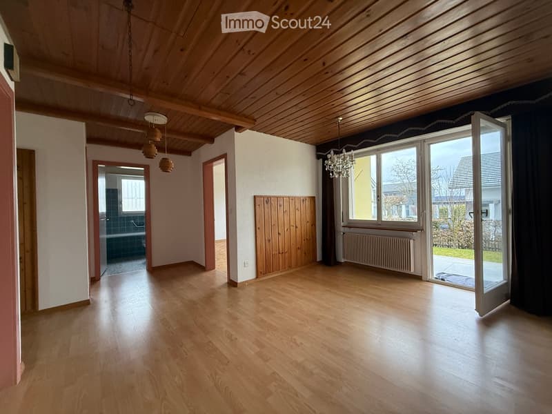 Empty room with wooden ceiling, wooden floor, large windows, wooden paneling, chandelier, wooden doors, radiator